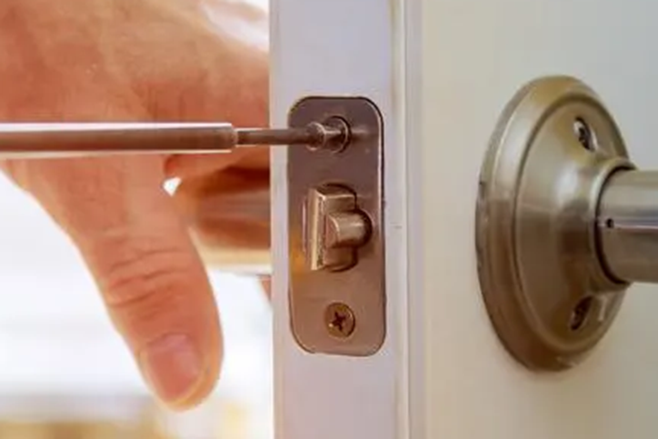 A Locksmith performing a hardware change on a commercial or residential lock.